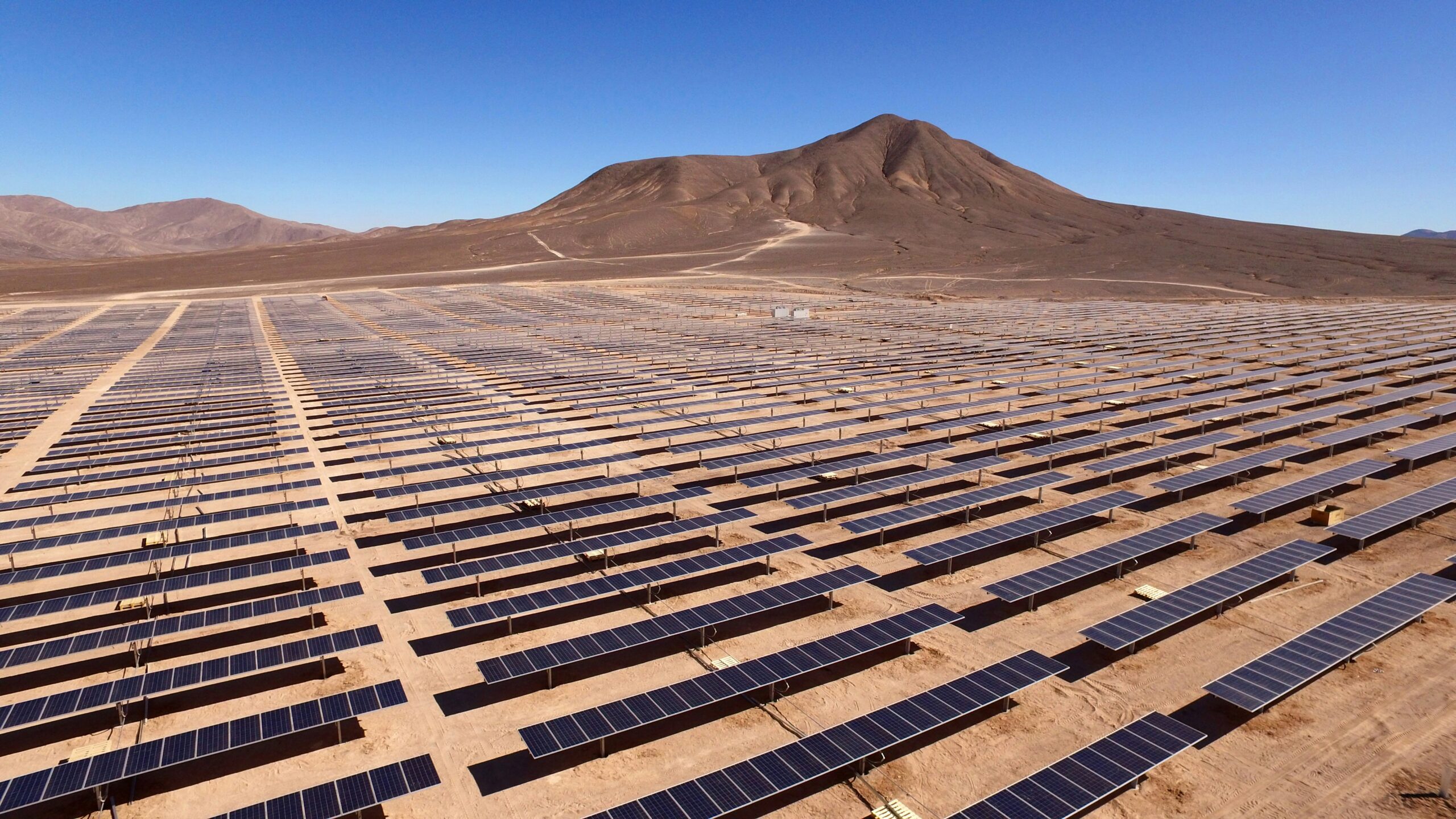 Large solar farm installation in a desert landscape with mountains in the background.